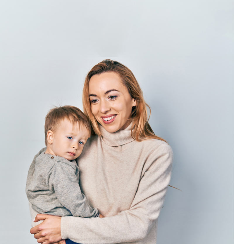 A young woman looks hopeful as she holds a small boy in her arms.